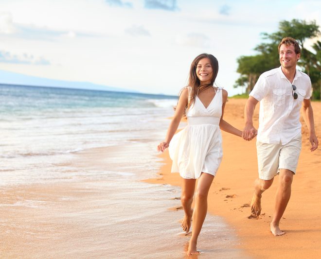 Beach couple on romantic travel honeymoon fun